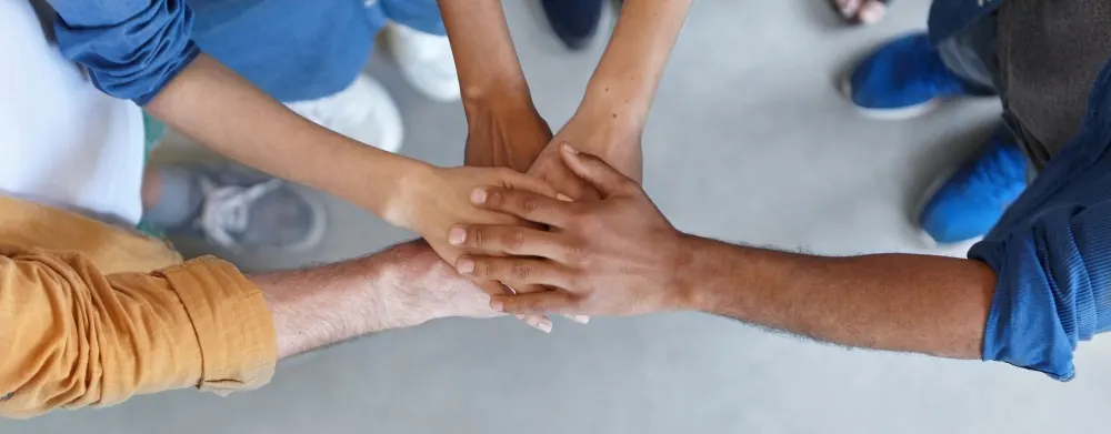 Team members joining hands together, symbolizing unity and support in facing unexpected challenges